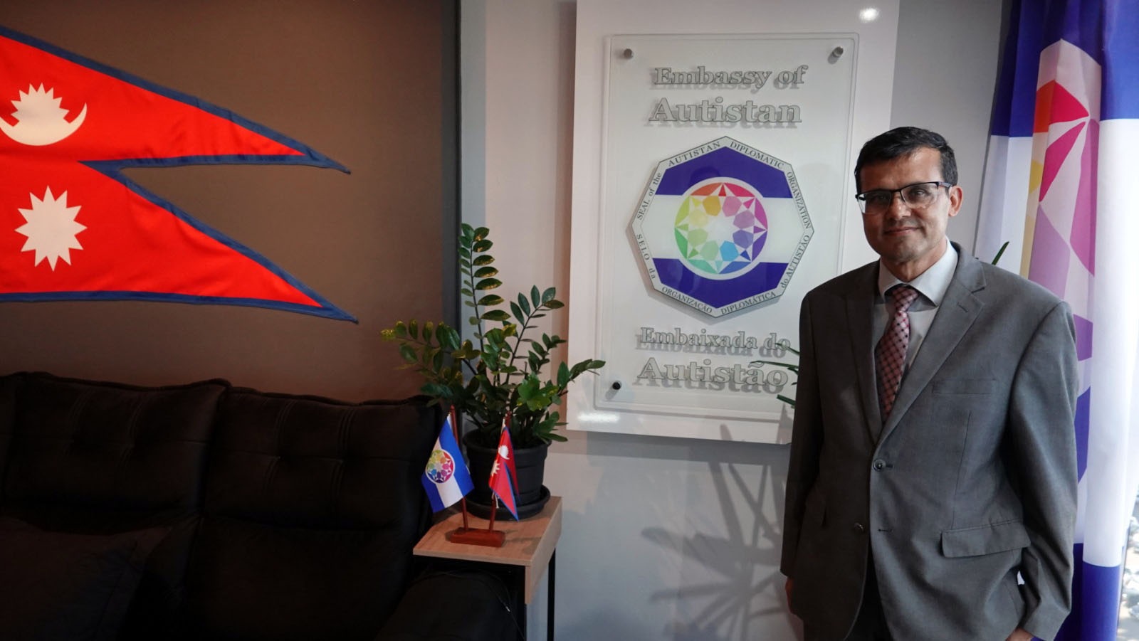 Perto da placa da Embaixada do Autistão, marcando o caráter simbólico da visita.